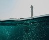 Une image prise sous l'eau dont le cadrage permet d'observer un phare en pleine mer